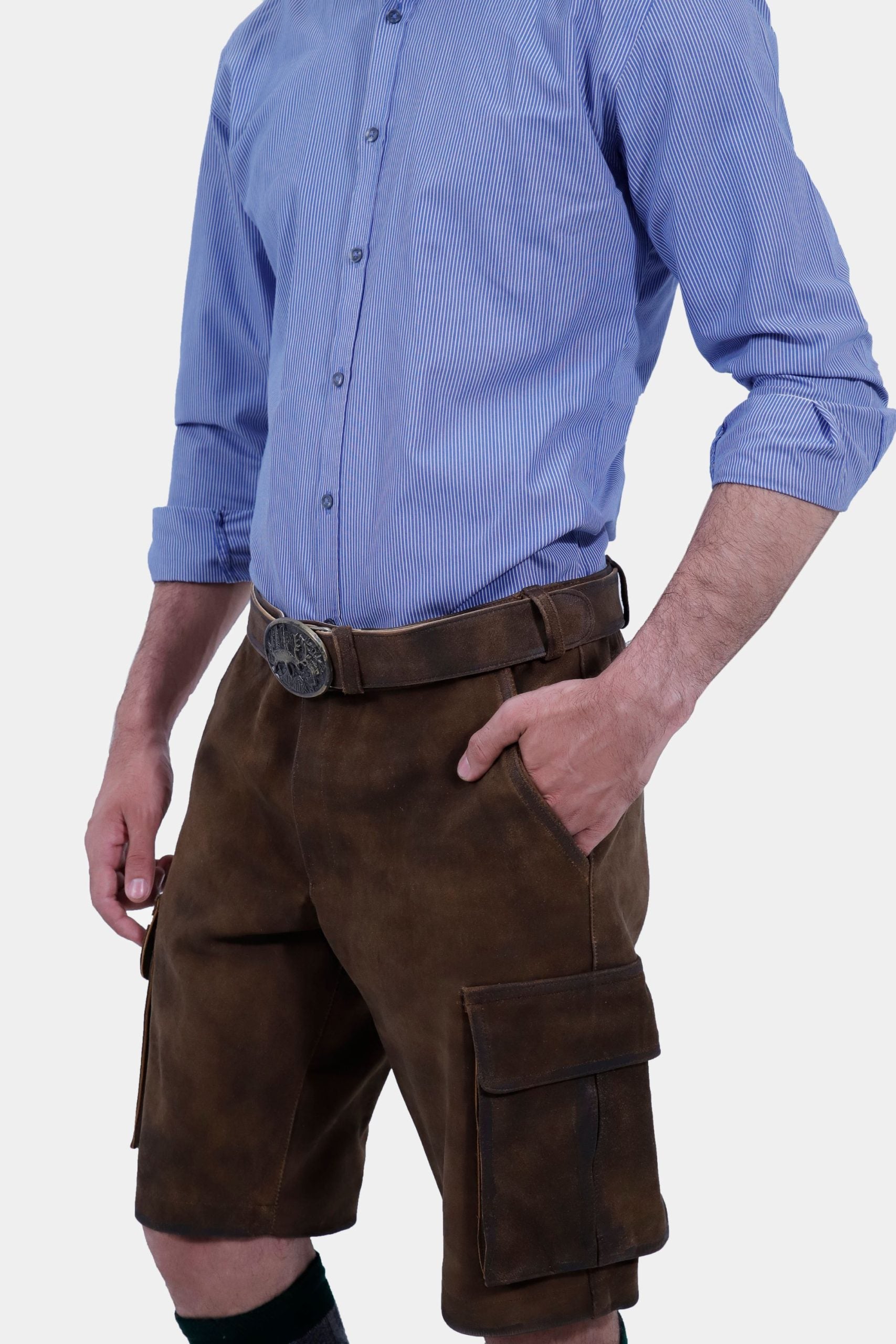 Side view of a man wearing traditional brown leather cargo Lederhosen paired with a blue striped shirt. The image highlights the side pockets and the belt buckle.