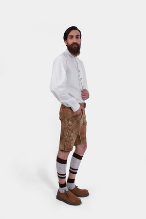 Side view of a bearded man standing confidently in Gerd Muller Lederhosen, complete with knee-high socks and traditional shoes.