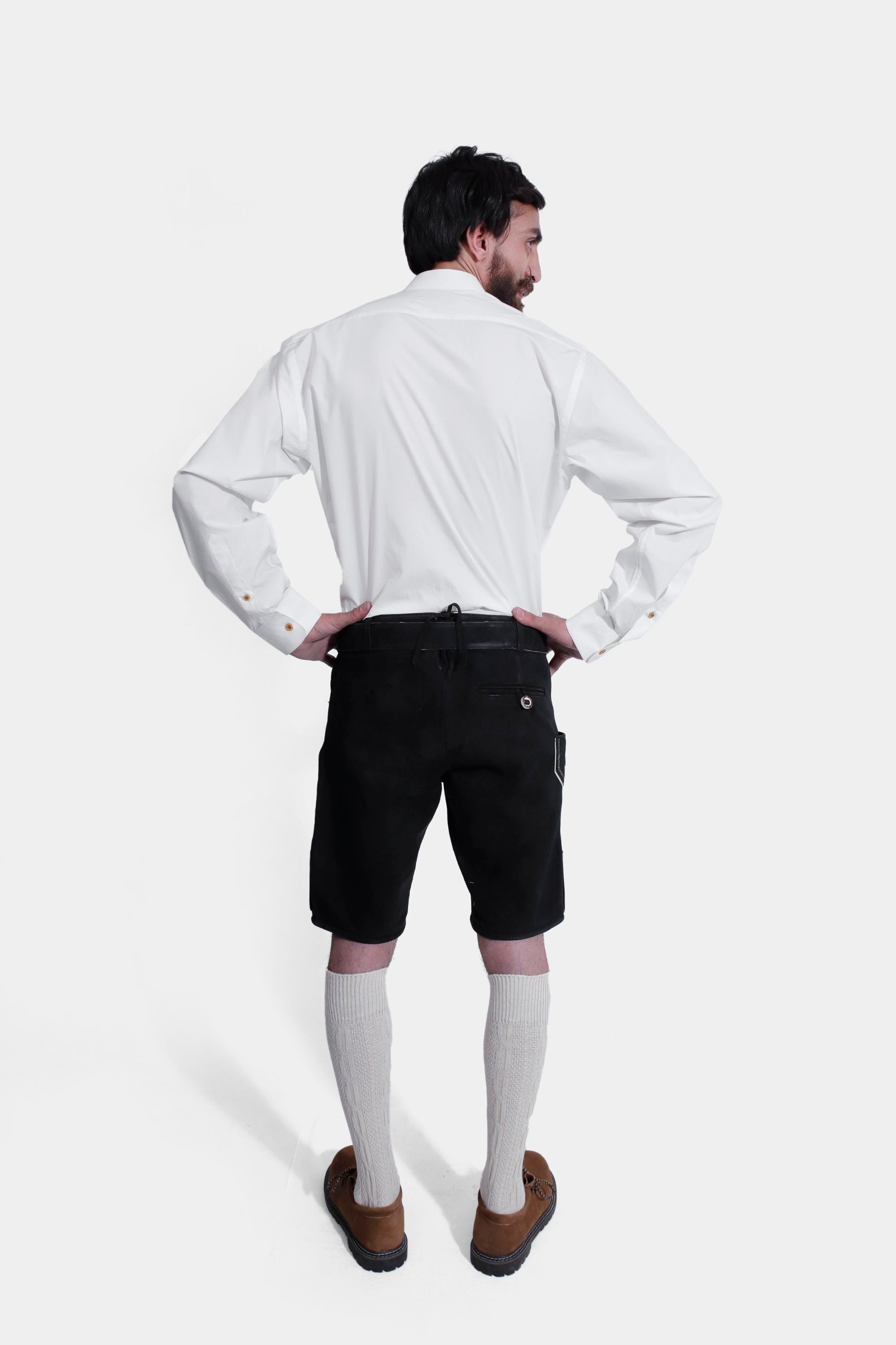 Back view of a man in a Hardy Kruger Lederhosen outfit, showing the rear details of the black Lederhosen shorts and the fit of the white shirt.