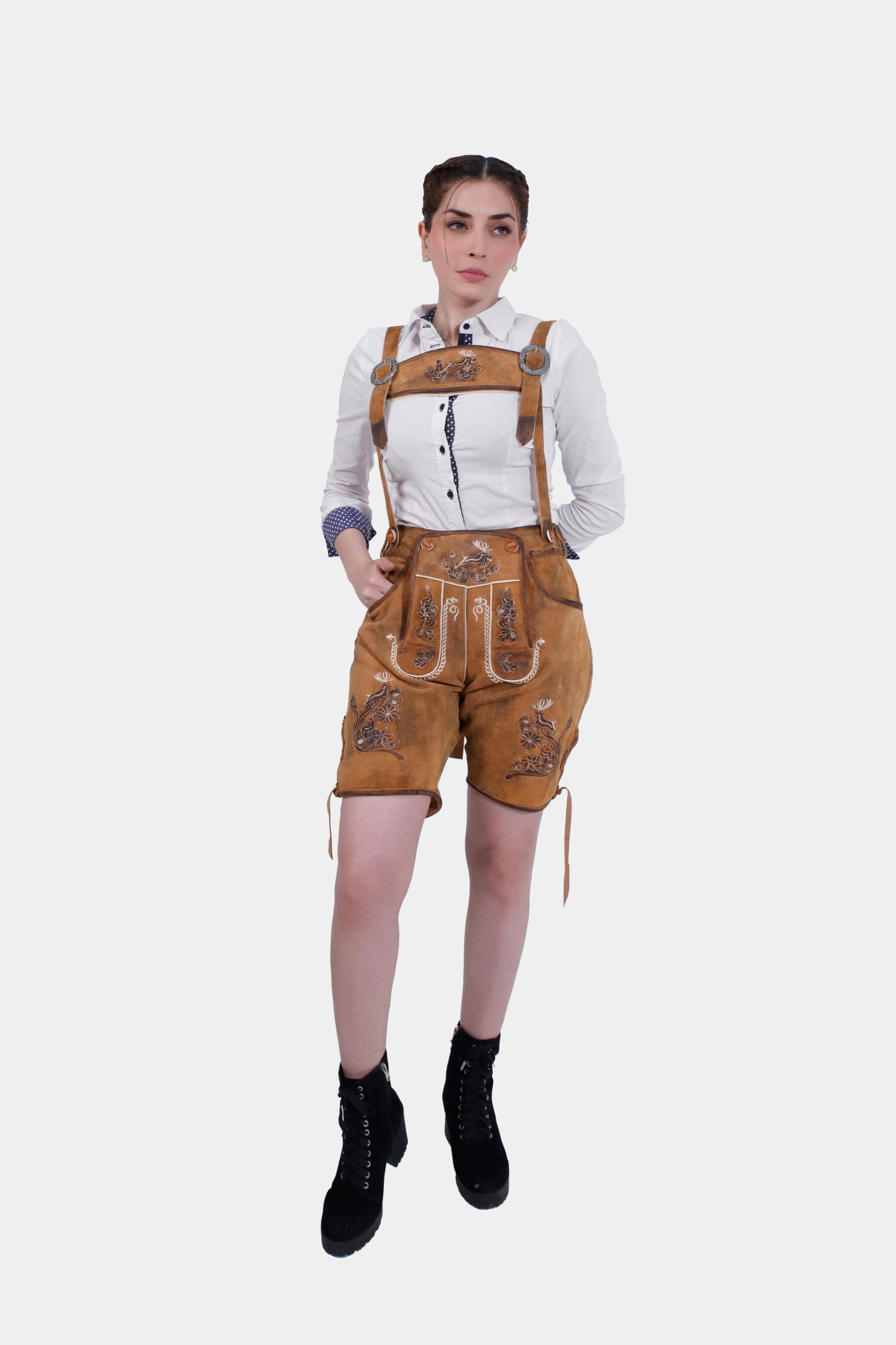 Full-body view of a woman wearing Hedy Lamarr Lederhosen and a white blouse with polka dot accents. The Lederhosen feature white embroidery and laces at the cuffs, styled with black ankle boots.