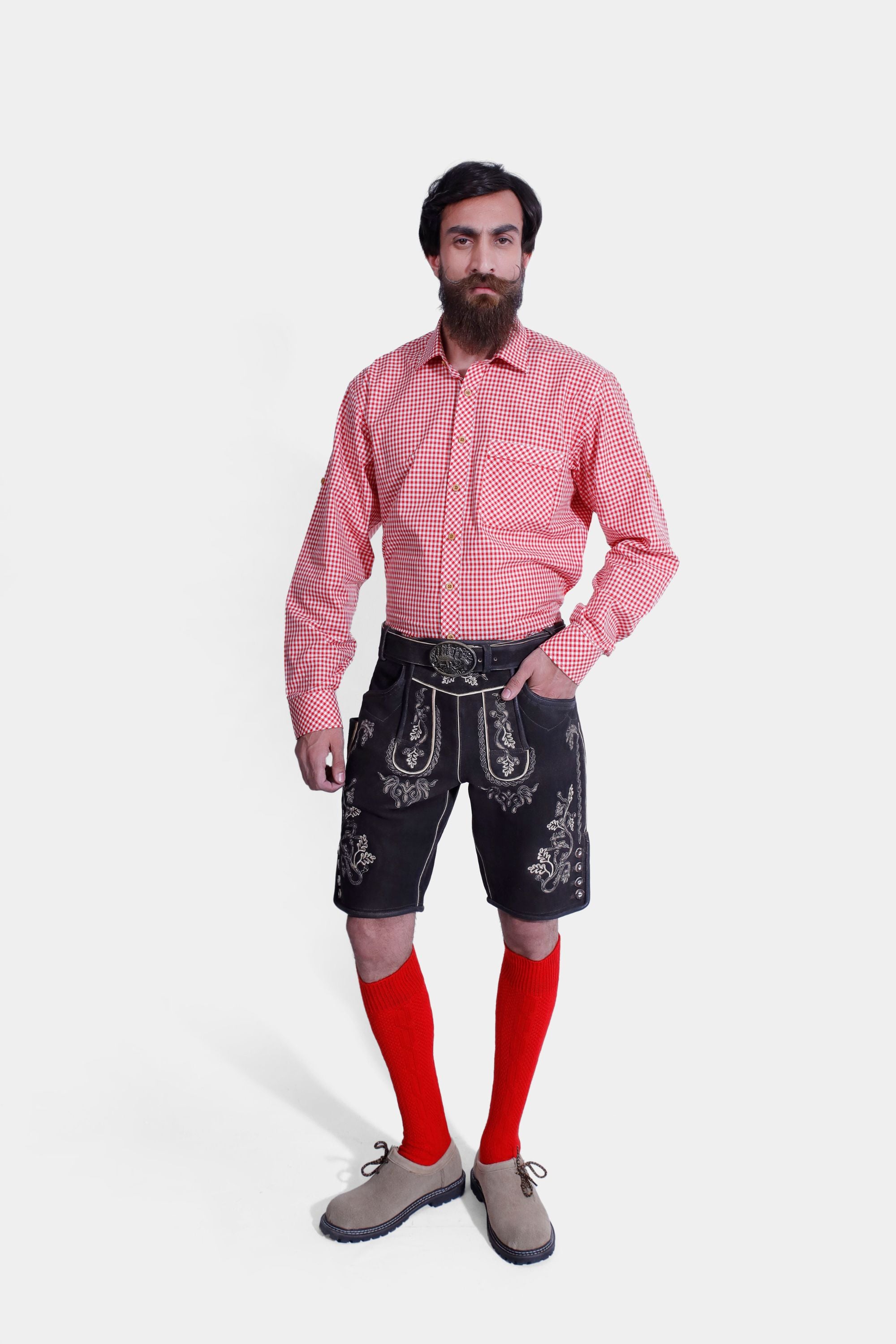 Man wearing the Hoffman Lederhosen Outfit featuring black embroidered Lederhosen, a red and white checkered shirt, and red knee-length socks.