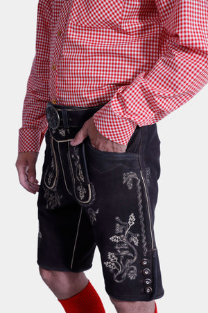 Close-up view of the Hoffman Lederhosen Outfit showing the detailed embroidery on the black Lederhosen, paired with a red and white checkered shirt.