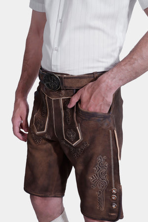 A side view of the man highlighting the pocket and detailed stitching on the brown lederhosen shorts.