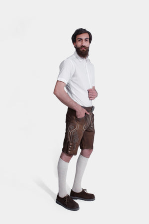 A other side view of the man wearing the brown leather lederhosen with suspenders, paired with the white shirt.