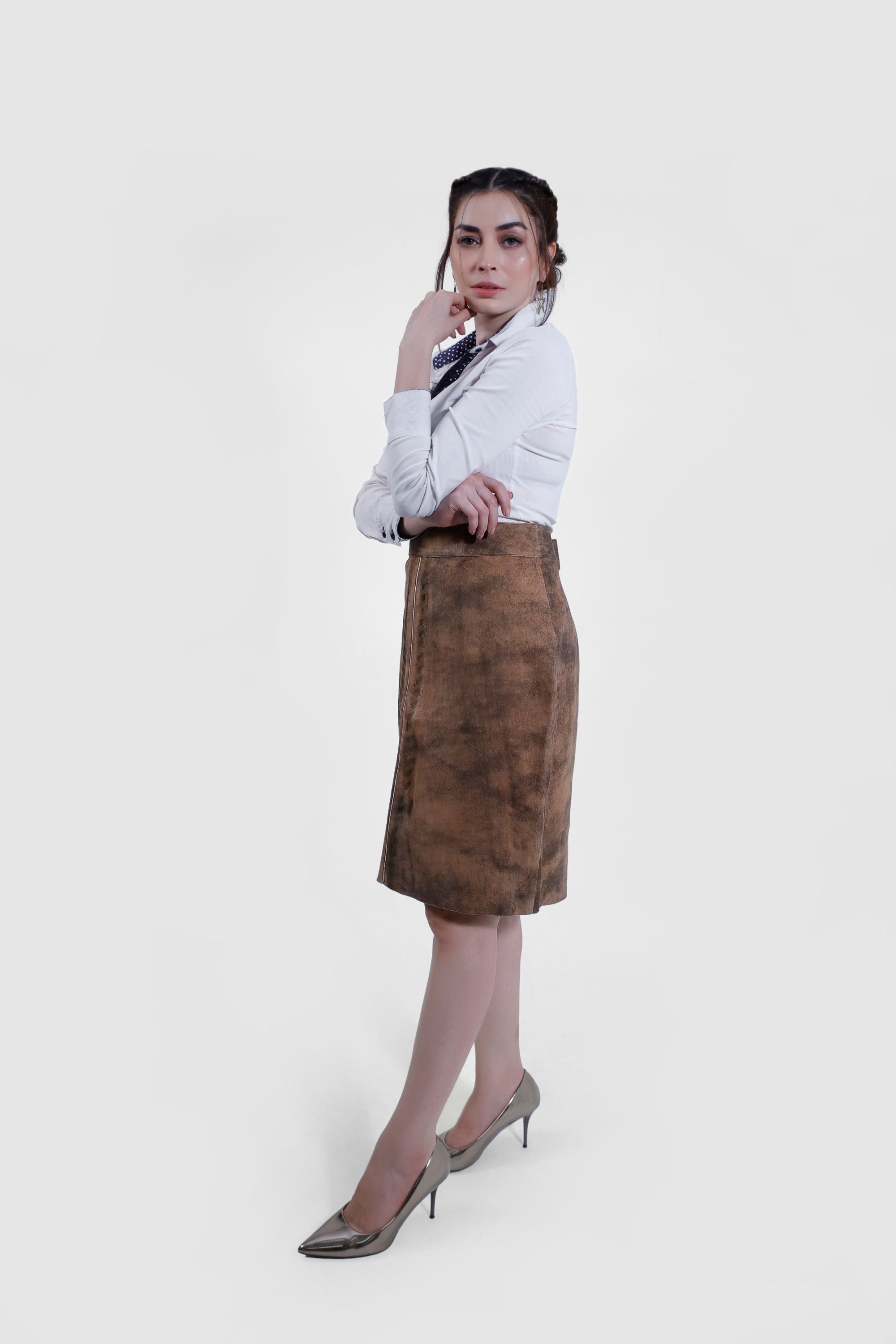Side profile view of of women wearing a traditional brown leather Karoline Lederhosen Skirt with subtle embroidery, paired with a white blouse featuring a polka-dotted inner collar