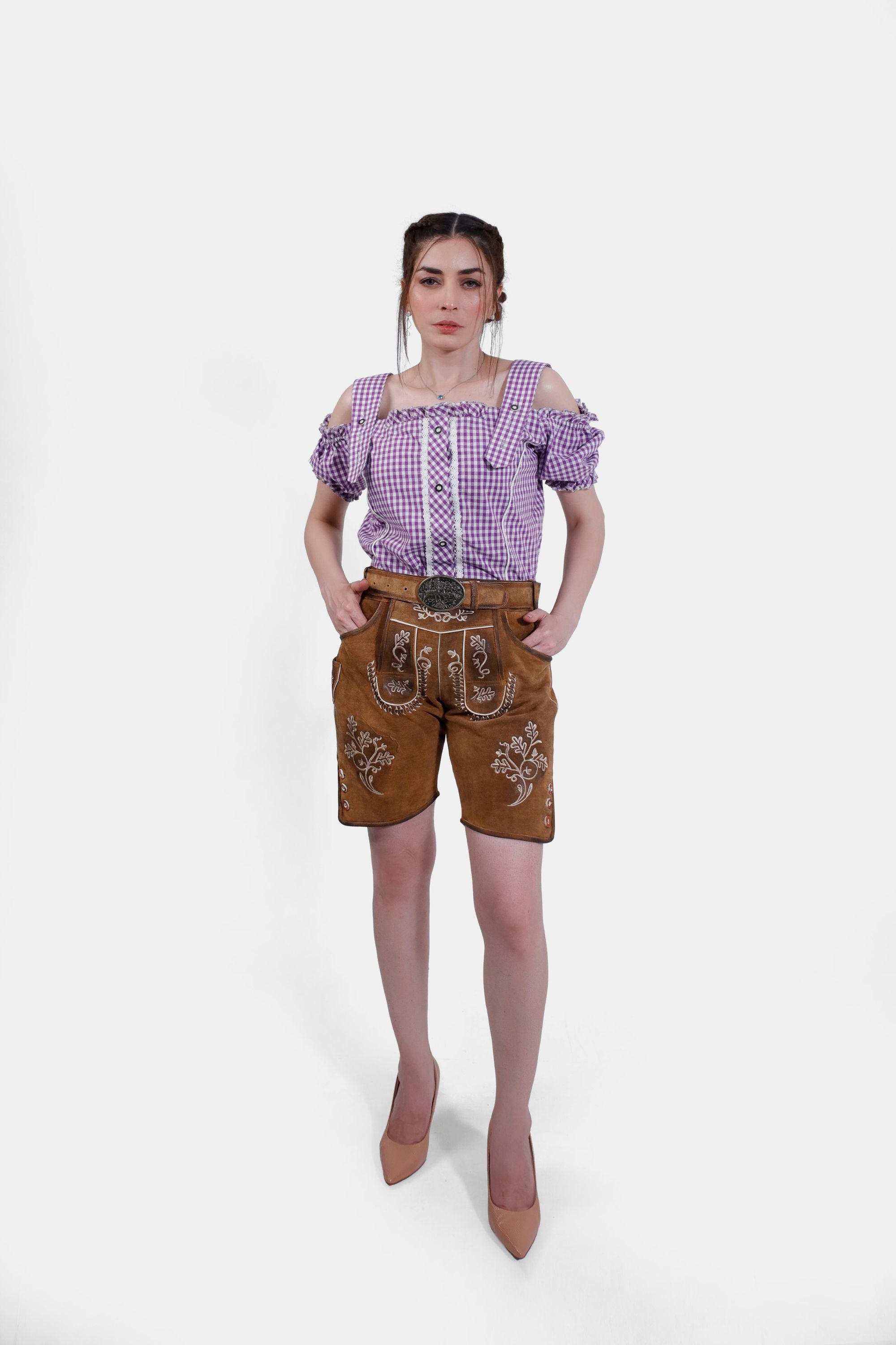 Model in brown leather lederhosen shorts with white embroidery paired with a purple checkered blouse, showcasing the front and side details of the outfit