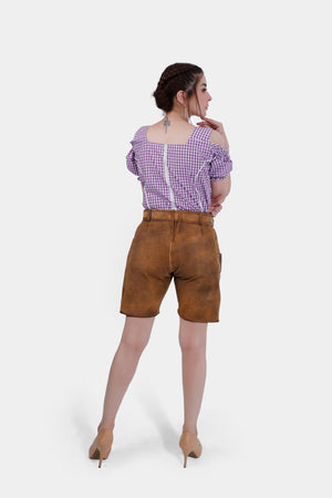Back view of a model in brown leather lederhosen shorts paired with a purple checkered blouse, showcasing the fit and style of the outfit.