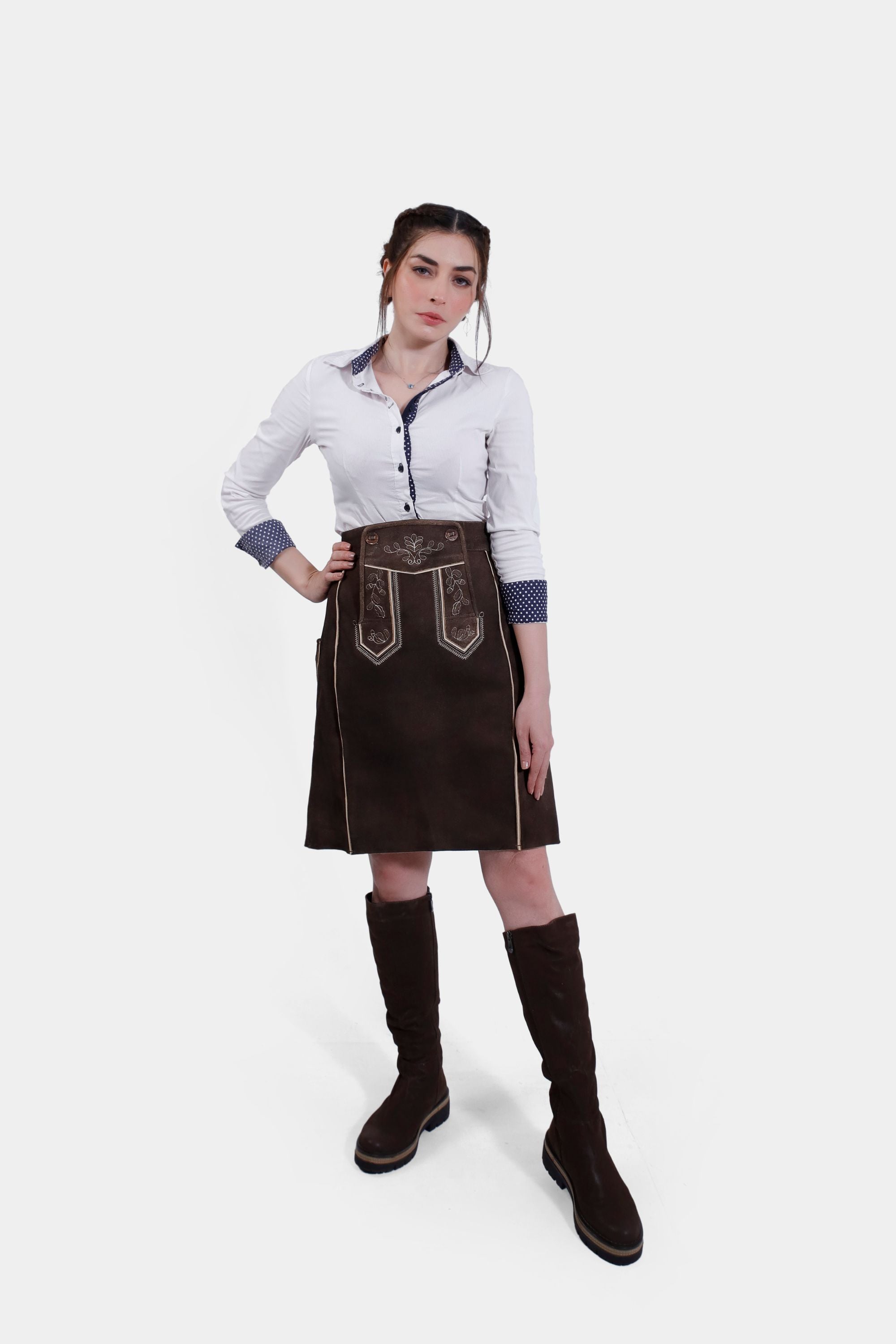 Full-body shot of a woman wearing the Lillian Lederhosen Skirt in Tyrolean Chocolate, styled with boots.