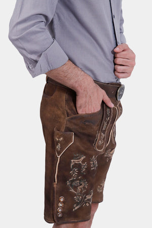 closed side view of the man in Lederhosen, highlighting the embroidered chest piece and traditional buckles.