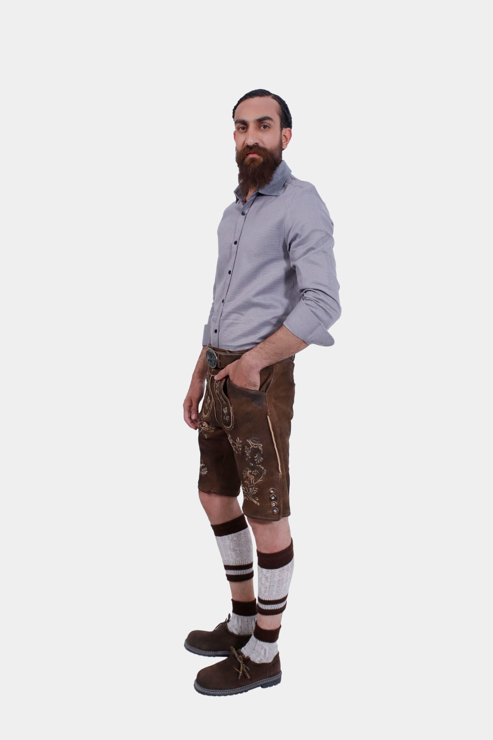 Side view of the man in Lederhosen, grey shirt, knee-high socks, and traditional shoes, standing with a neutral expression.