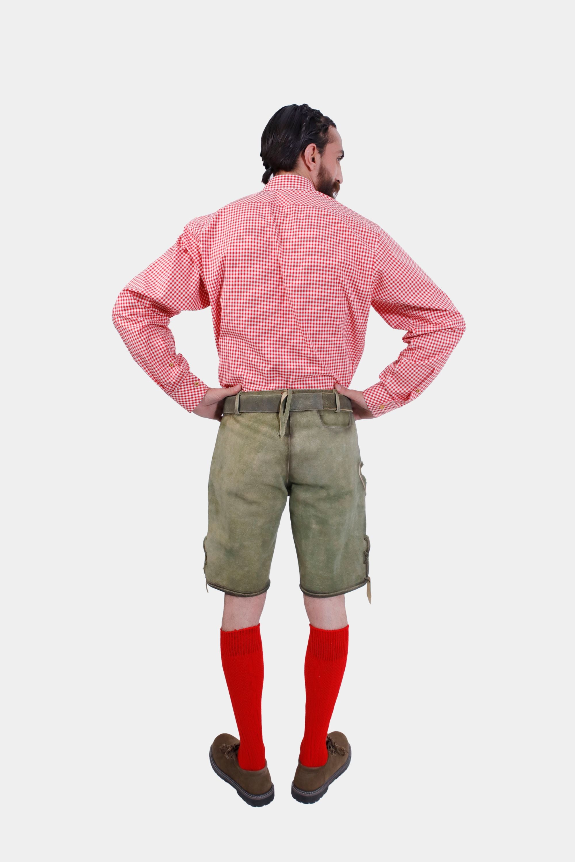 Rear view of a man wearing traditional German lederhosen with a red checkered shirt, hands on hips.
