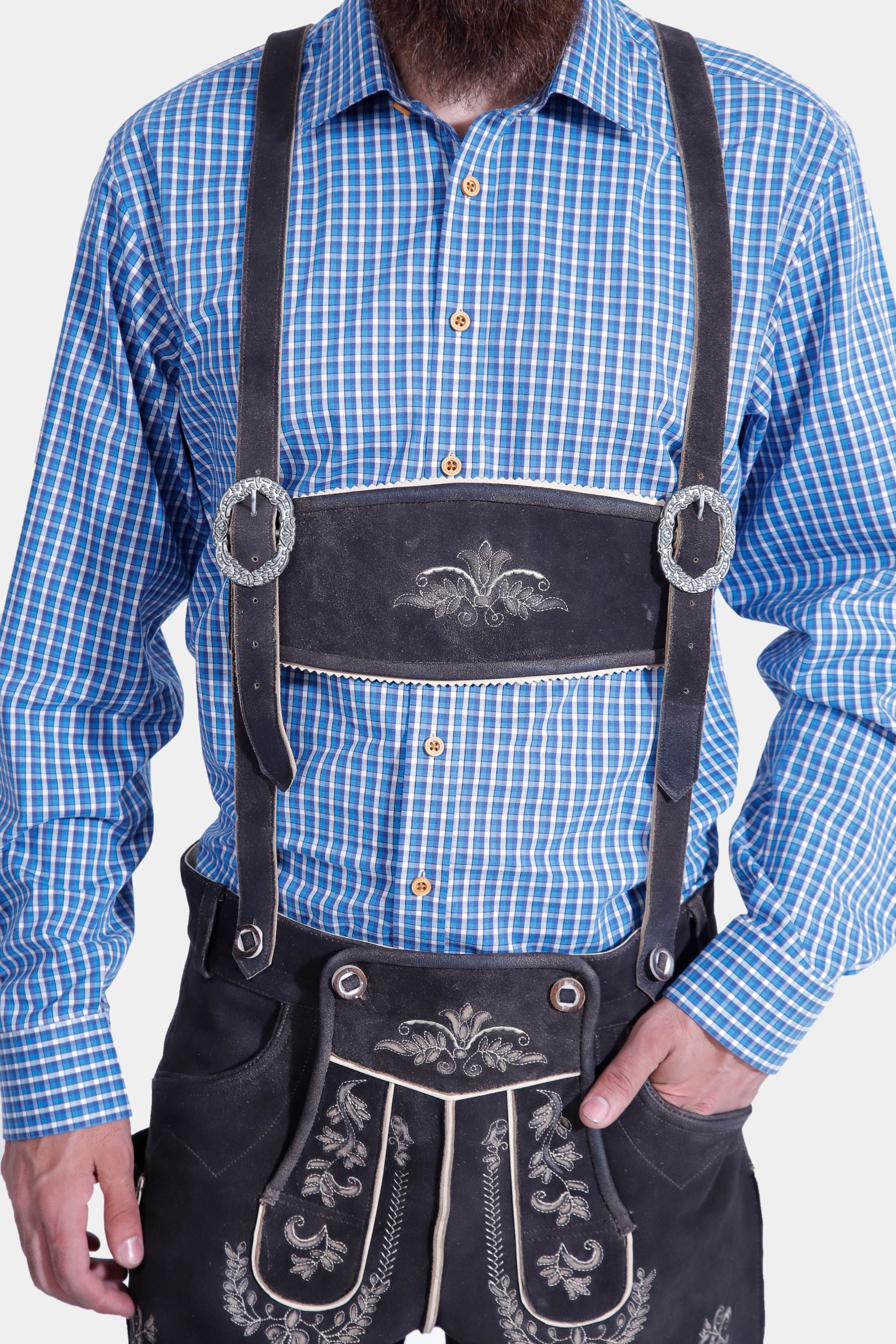 A close-up of the man in Mountain Majesty Lederhosen, highlighting the detailed front embroidery and the shirt.