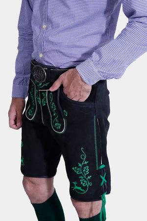A close-up view of the Mueller Lederhosen with suspenders, showing the detailed embroidery on the bib, worn with a blue checkered shirt.