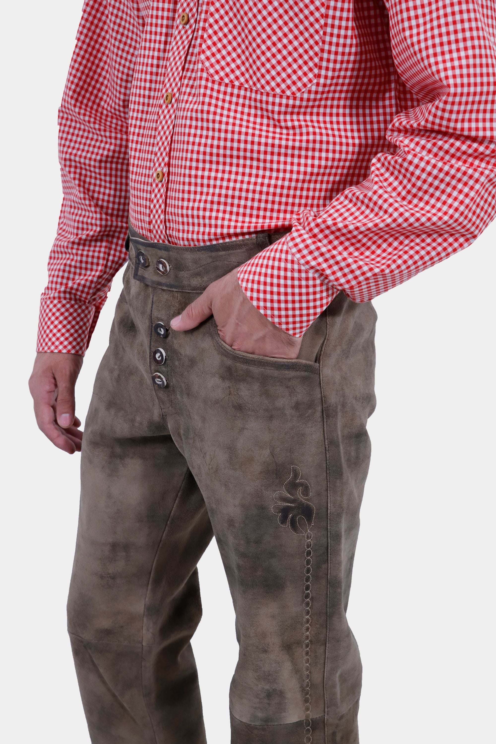 Closed side view of a man wearing lederhosen long paired with red checkered shirt and brown matching shoes