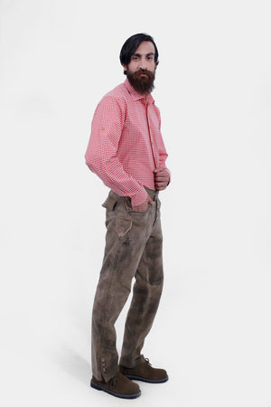 Complete side view of a man wearing lederhosen long paired with red checkered shirt and brown matching shoes