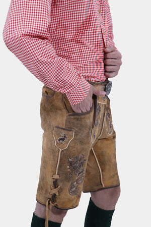 Side profile of a man dressed in Oktoberfest Tulsa Lederhosen and a red gingham shirt, highlighting the side ties and embroidery of the lederhosen.