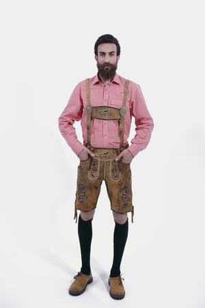 A man wearing Oktoberfest Tulsa Lederhosen suspenders featuring decorative buckles and embroidered leather, paired with a red and white checked shirt.
