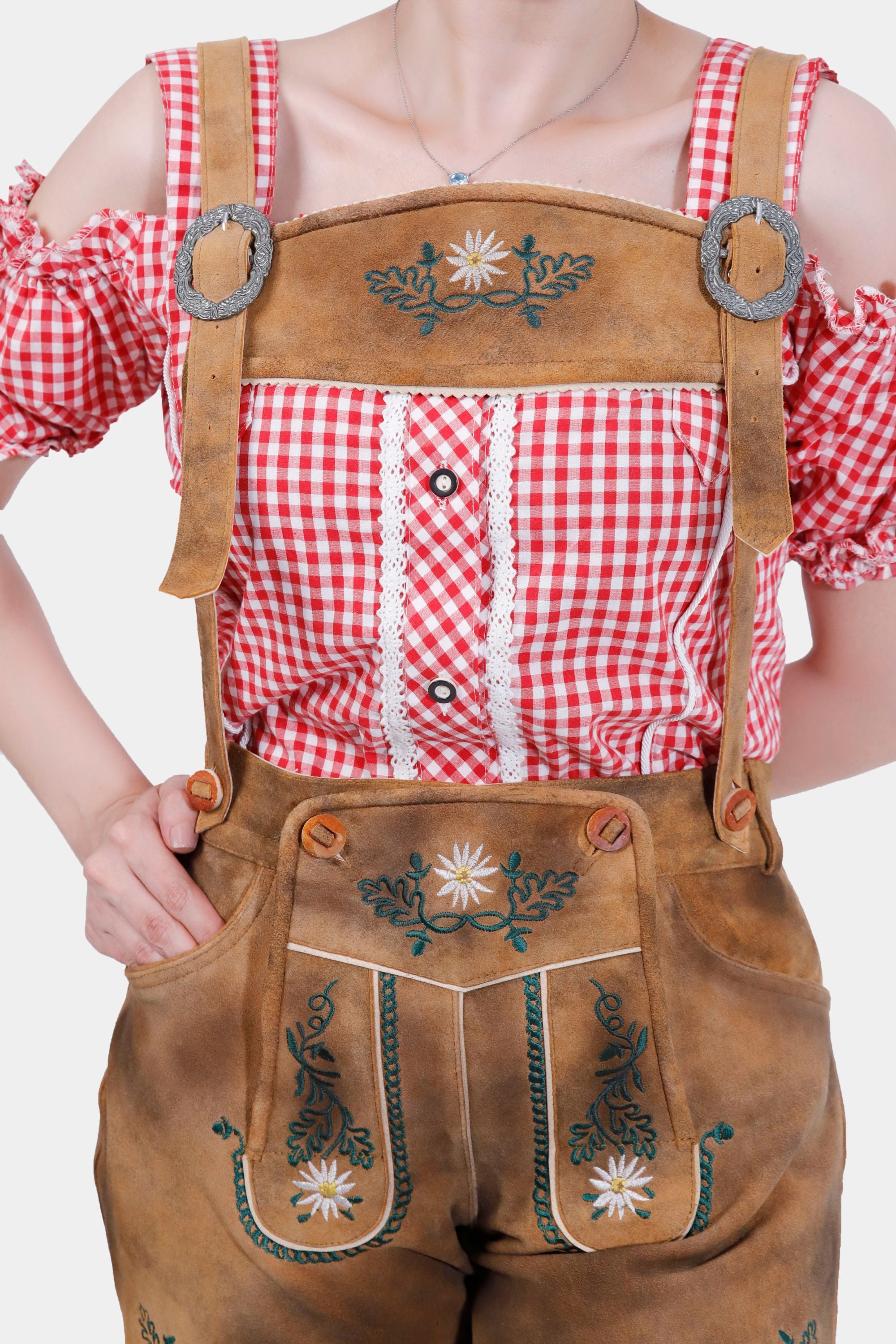Close-up of Olivia Rodrigo Lederhosen showcasing intricate natural color embroidery on the bib and legs, with a red checkered top.