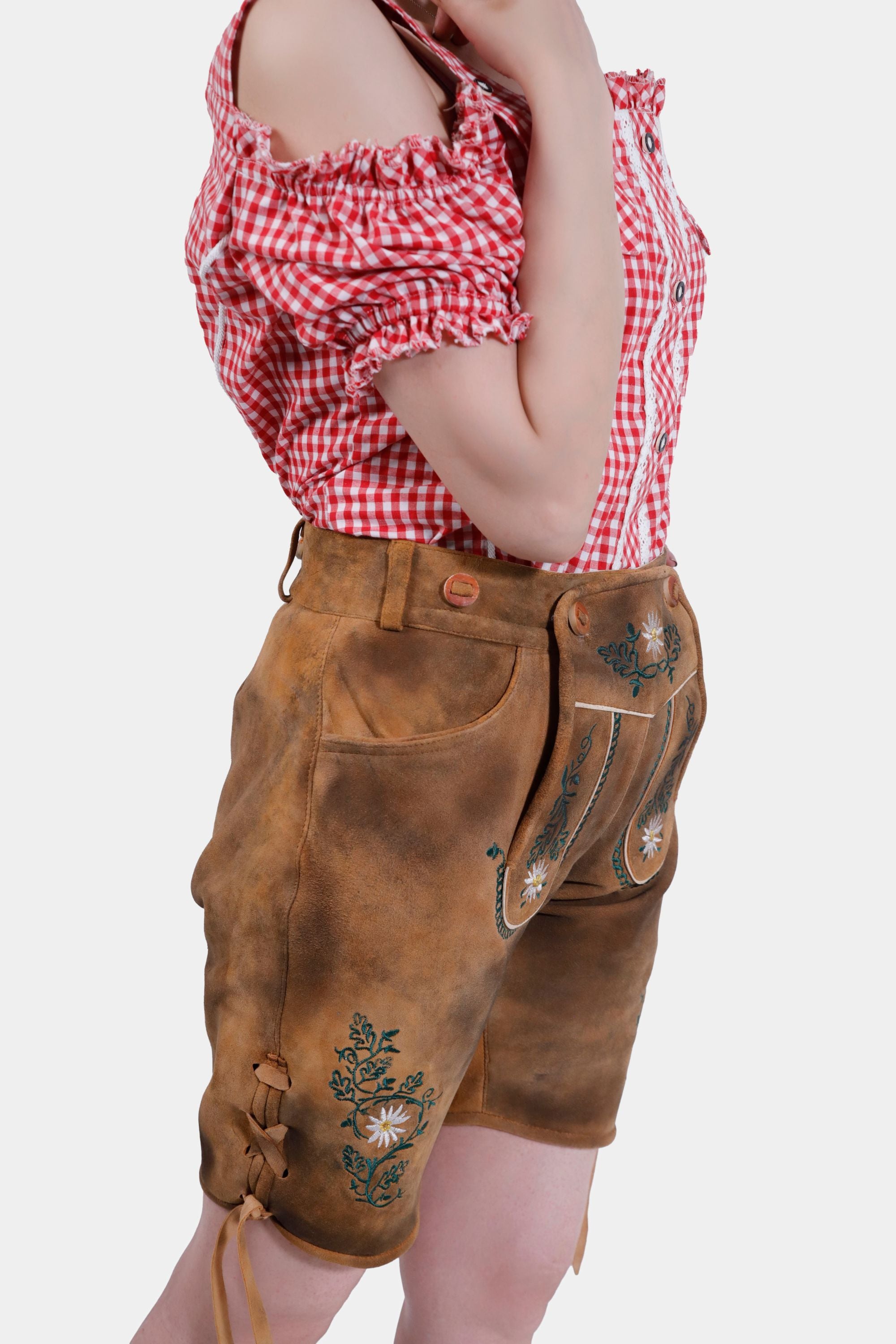 Side view of Olivia Rodrigo Lederhosen highlighting the side knife pocket and detailed embroidery, worn with a red checkered top.