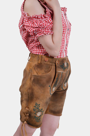 Side view of Olivia Rodrigo Lederhosen highlighting the side knife pocket and detailed embroidery, worn with a red checkered top.