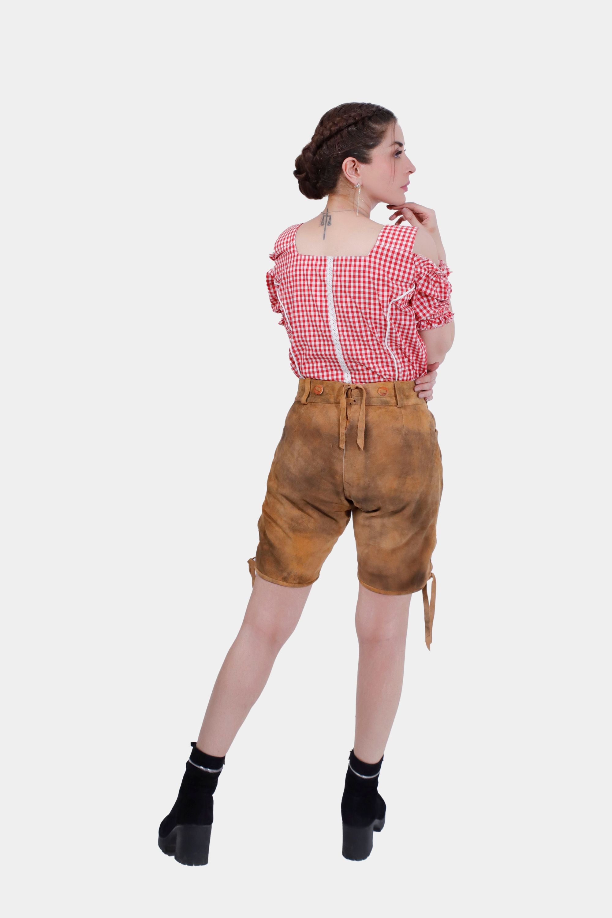 Full body back view of Olivia Rodrigo Lederhosen, showing the complete traditional look with black boots and a red checkered top.