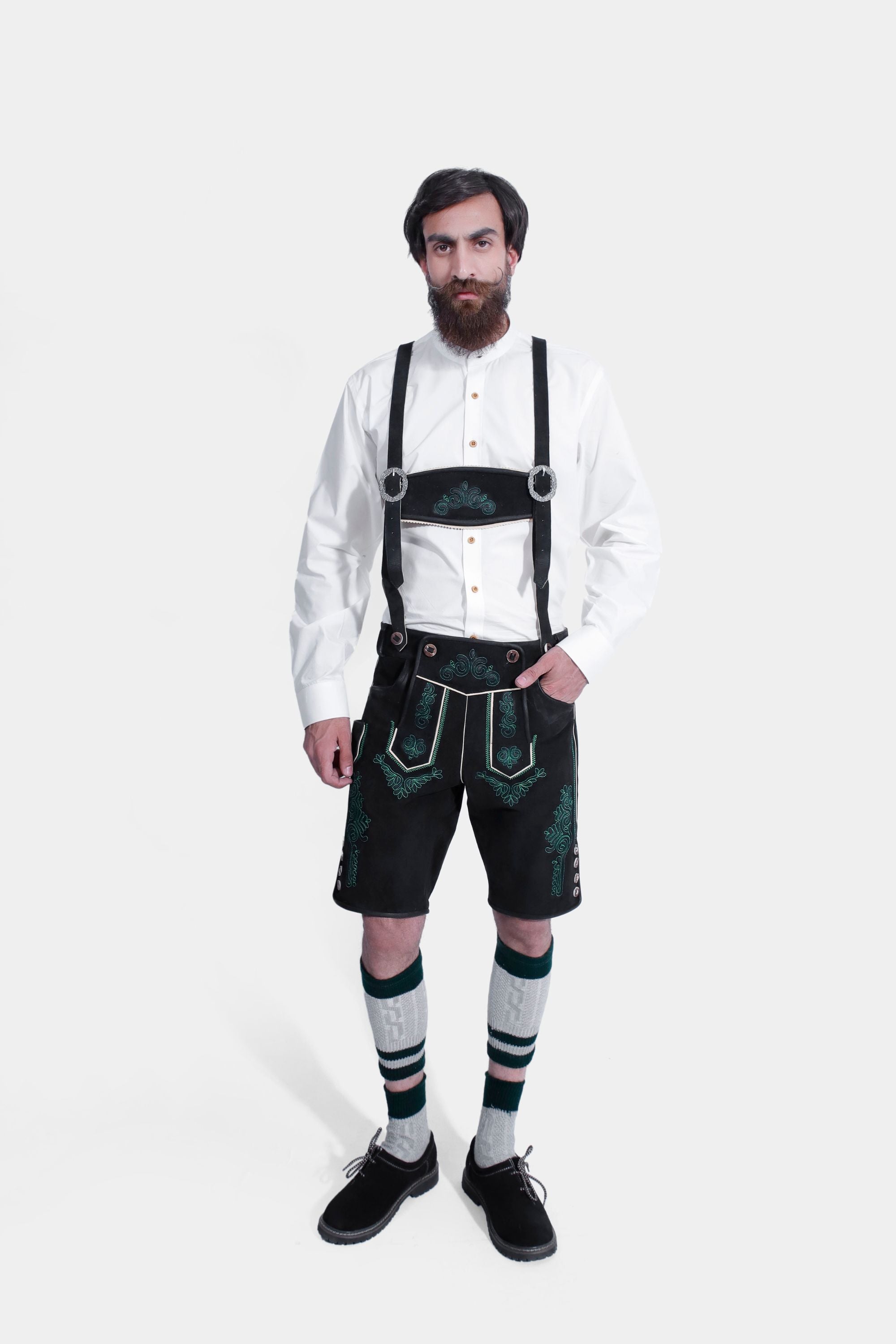The man seen from the back, showcasing the rear design of the black Lederhosen and the fit of the white Bavarian shirt, complete with knee-high socks and black shoes.
