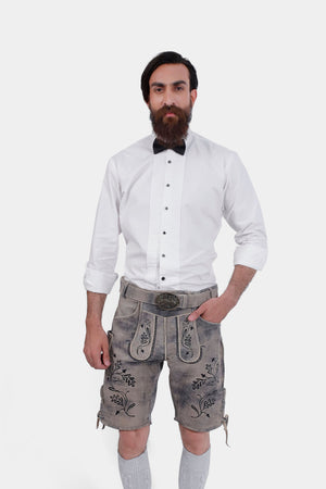 Man wearing Staffelsee Sunset Lederhosen in Oktoberfest Oak color, posing with hands in pockets and wearing a white shirt and bow tie