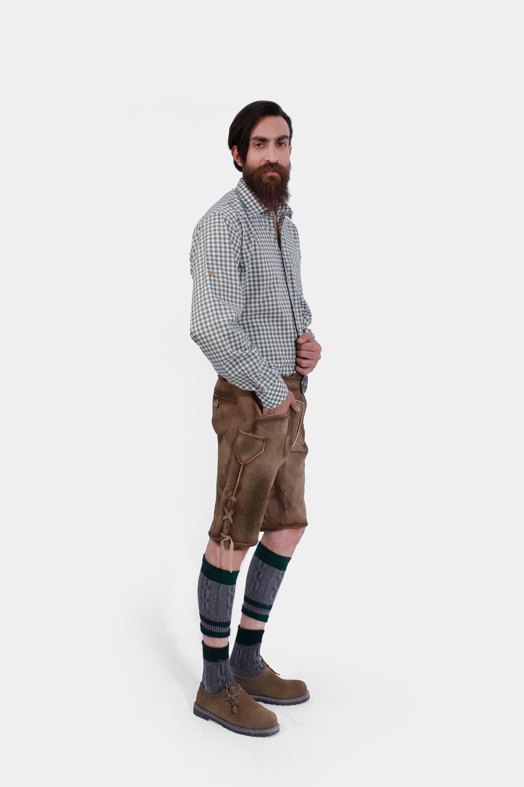Man wearing Thuringian Forest Dragons Lederhosen with a checkered shirt and knee-high socks, posing from the side