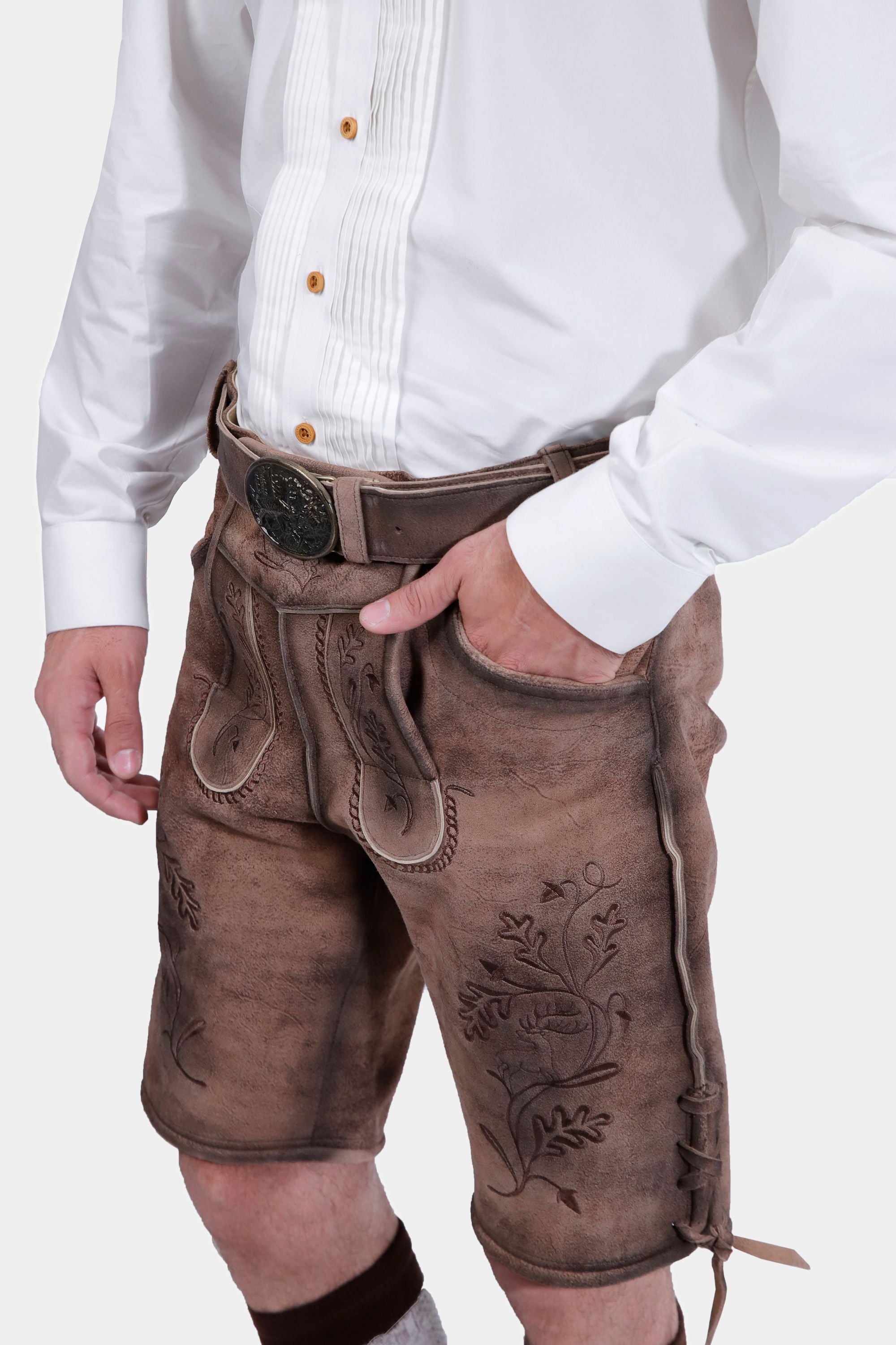 Closed side view of a man wearing Timber Trail Lederhosen in Caramel Earth with natural embroidery, goat suede leather, and multiple pockets.