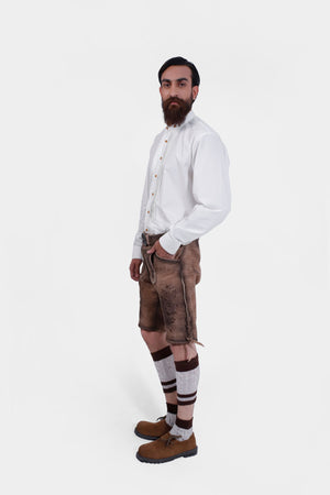 Side view of a man wearing Timber Trail Lederhosen in Caramel Earth with natural embroidery, goat suede leather, and multiple pockets.