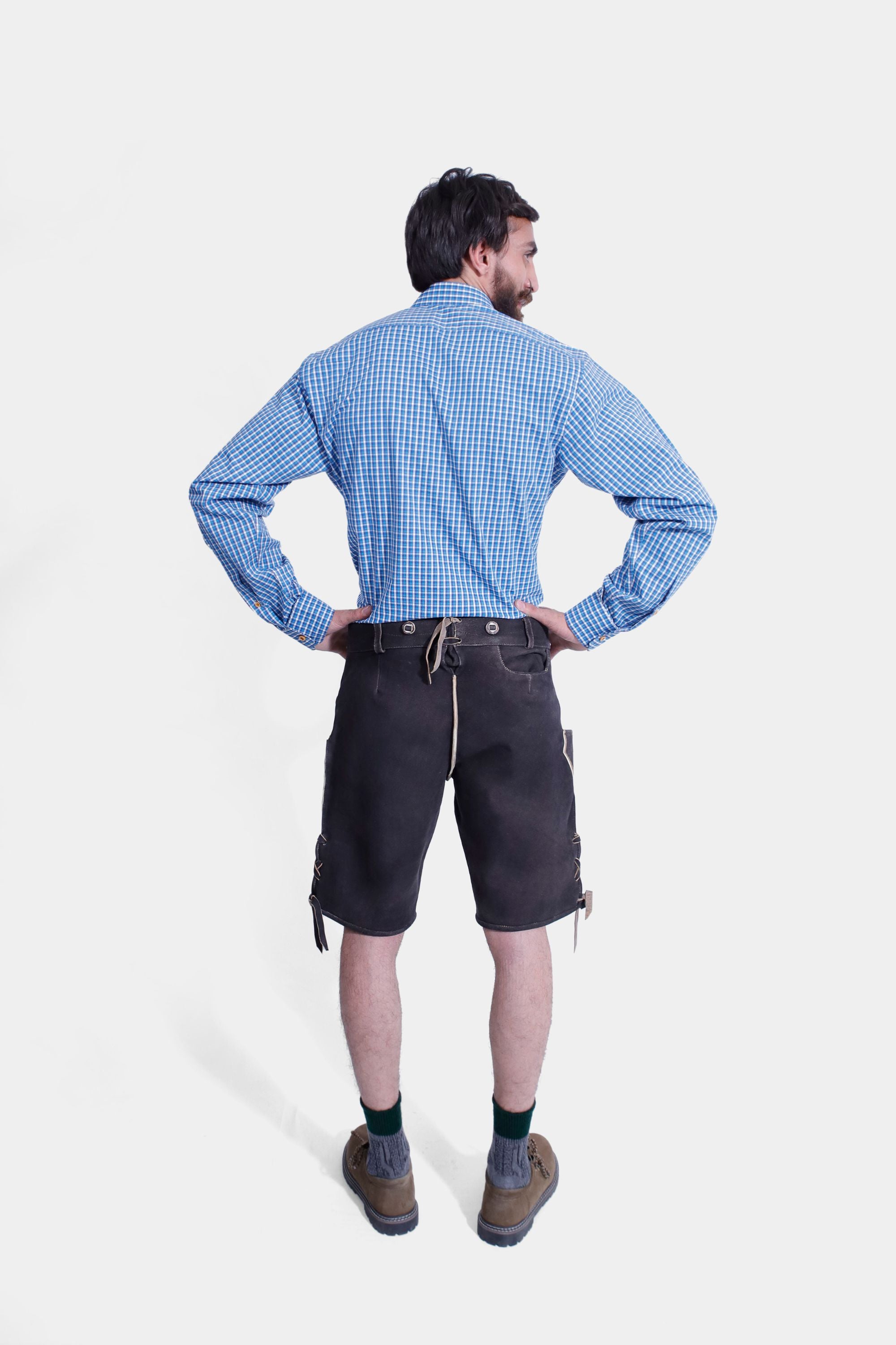 "Back view of a man in the Gert Fröbe Lederhosen Outfit, displaying the fit of the blue checkered shirt and the black leather shorts with embroidery."