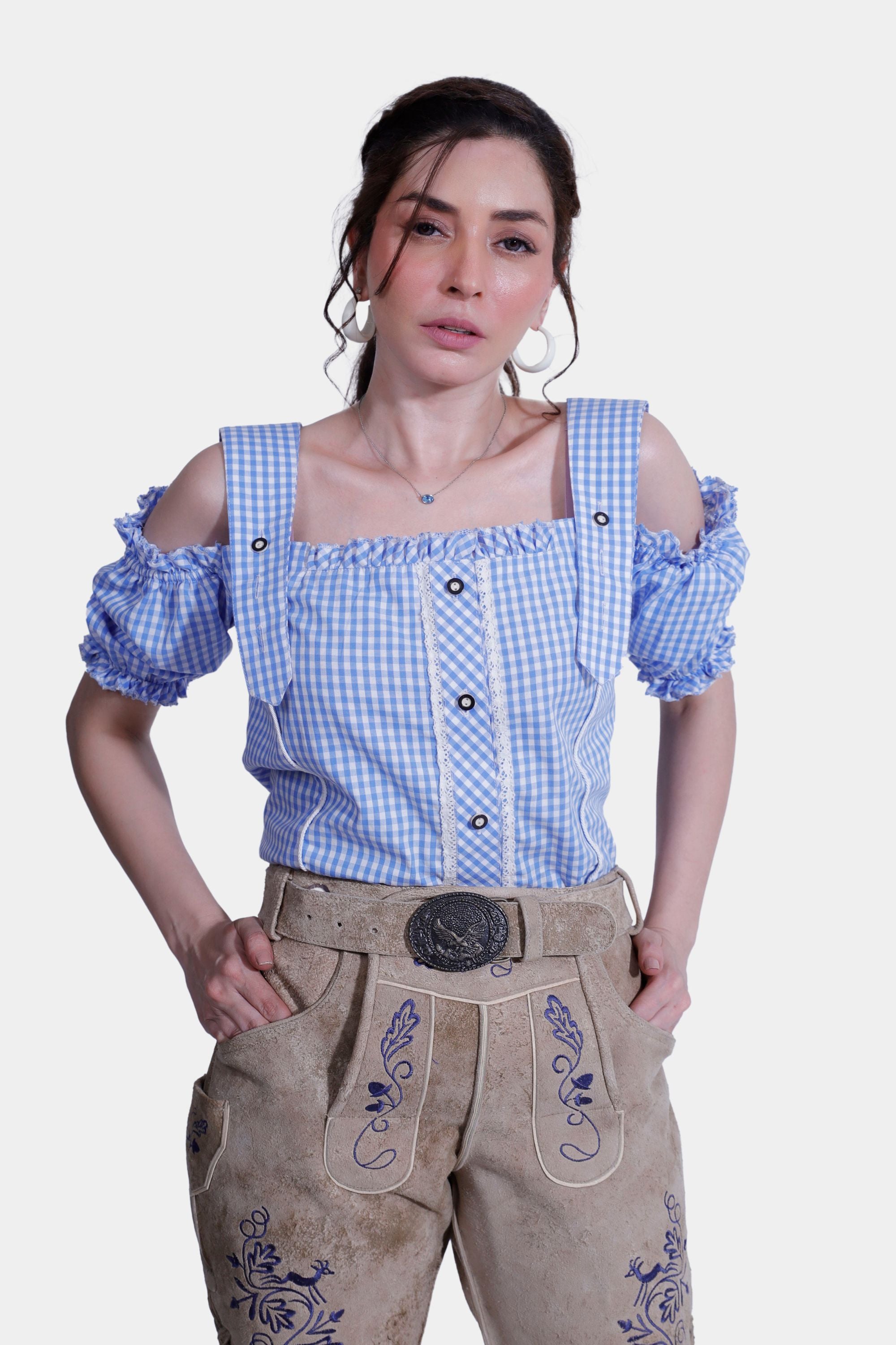 Close-up of a woman wearing a blue checkered blouse and beige Lederhosen shorts, showcasing the embroidery details on the shorts.