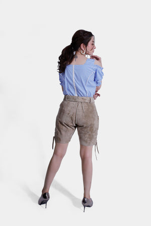 Rear view of a woman wearing beige Lederhosen shorts and a blue checkered blouse, with her hair tied back, showcasing the back details of the outfit.
