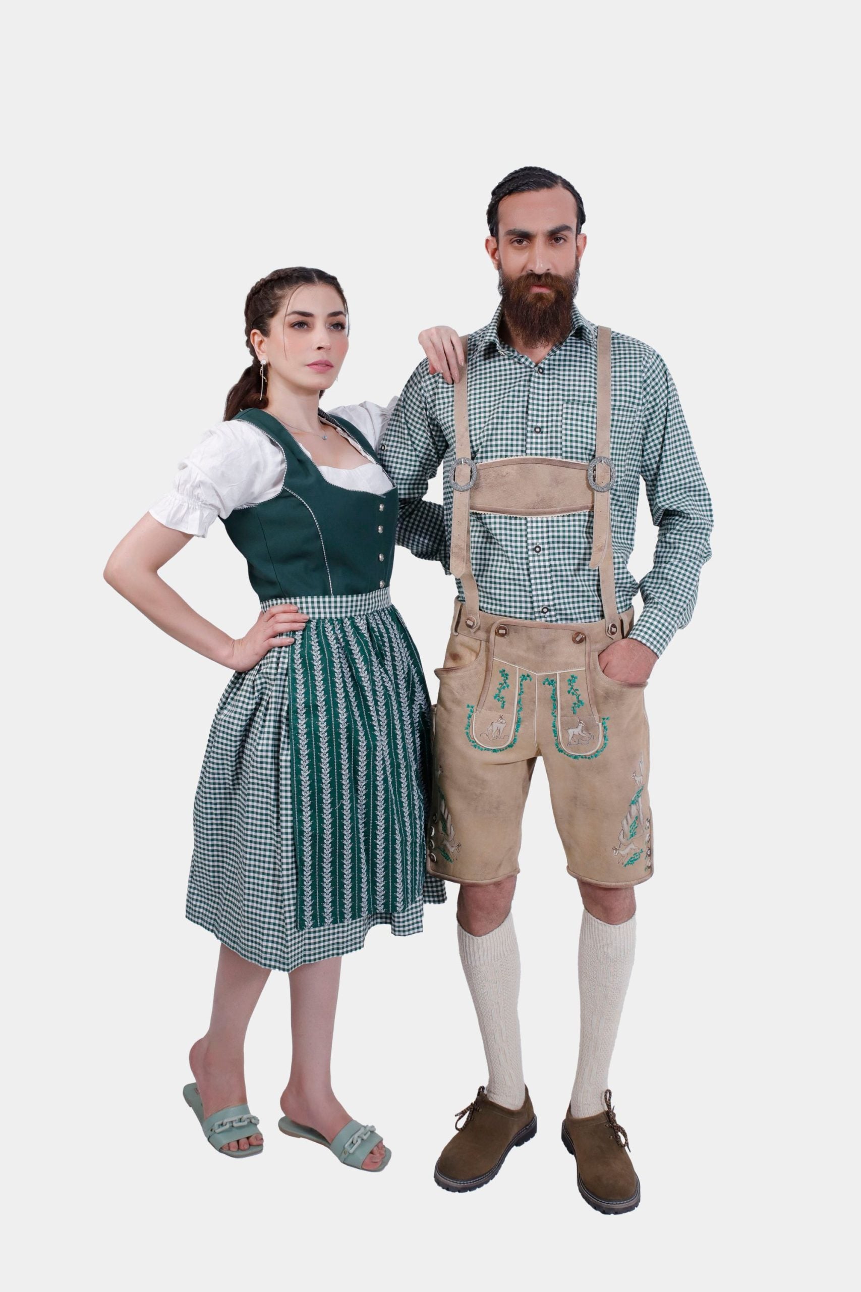 A man and woman in traditional Bavarian attire. The woman is wearing a green dirndl dress with a white blouse, while the man is dressed in beige lederhosen with green embroidery and a green checkered shirt. Both stand confidently, showcasing their stylish and coordinated outfits.
