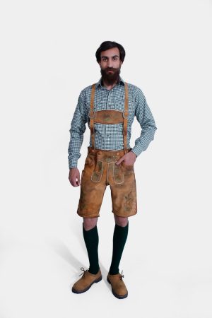 The man is fully dressed in the lederhosen with suspenders, standing in a frontal pose. His outfit is complete with green knee-high socks and brown shoes, emphasizing the traditional Bavarian look.