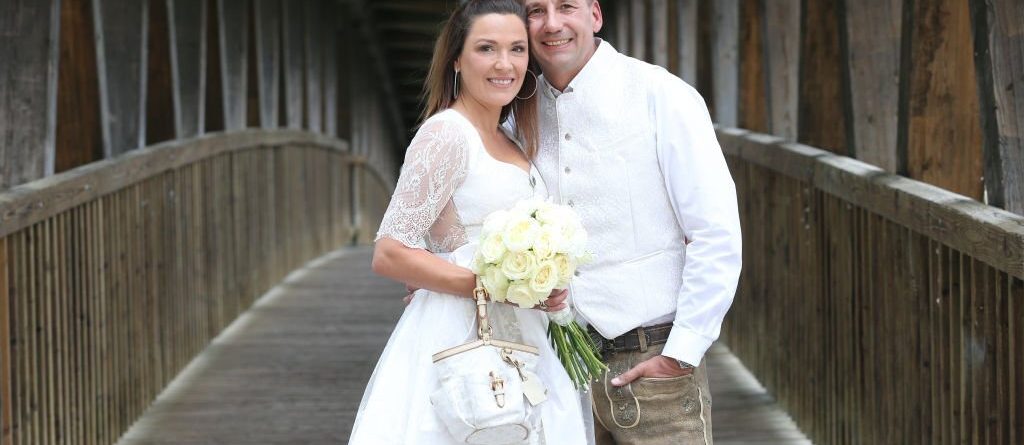 Bavarian man and woman wearing lederhosen and dirndl own their civil wedding.