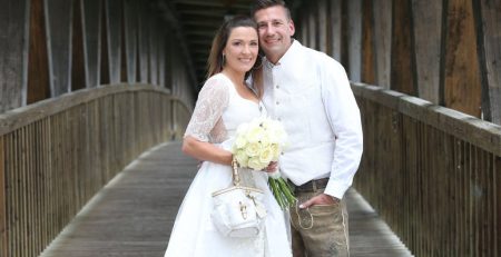 Bavarian man and woman wearing lederhosen and dirndl own their civil wedding.