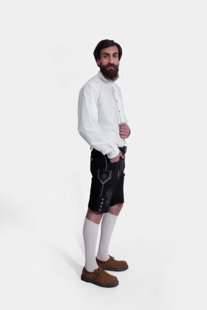 Side view of a man wearing Black Edelweiss Lederhosen in Obsidian Twilight with natural embroidery, white shirt, and traditional knee-high socks.