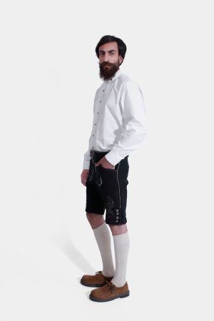 Side view of a man wearing Black Edelweiss Lederhosen in Obsidian Twilight with natural embroidery, white shirt, and traditional knee-high socks.