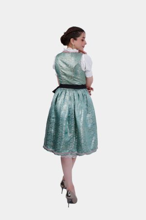 A back view of the dirndl, showing the green fabric with subtle floral patterns. The black ribbon is tied at the back, and the woman’s hair is styled in a braid.