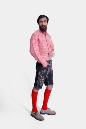 Angled side view of man wearing black Lahm Lederhosen with white embroidery, showcasing the detailed side panel and overall fit, paired with a red checkered shirt and red knee-high socks.