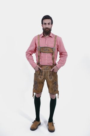 A man wearing Oktoberfest Tulsa Lederhosen suspenders featuring decorative buckles and embroidered leather, paired with a red and white checked shirt.