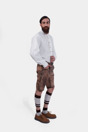 Side view of a man wearing Timber Trail Lederhosen in Caramel Earth with natural embroidery, goat suede leather, and multiple pockets.