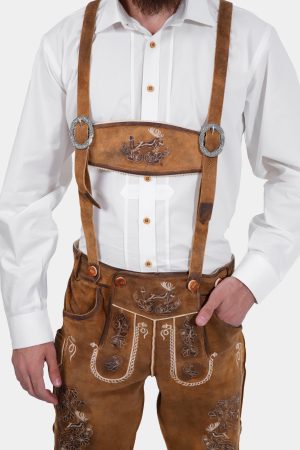 Close-up of a man wearing a white dress shirt and brown lederhosen with suspenders. The suspenders feature decorative embroidery, including a deer motif on the front strap.